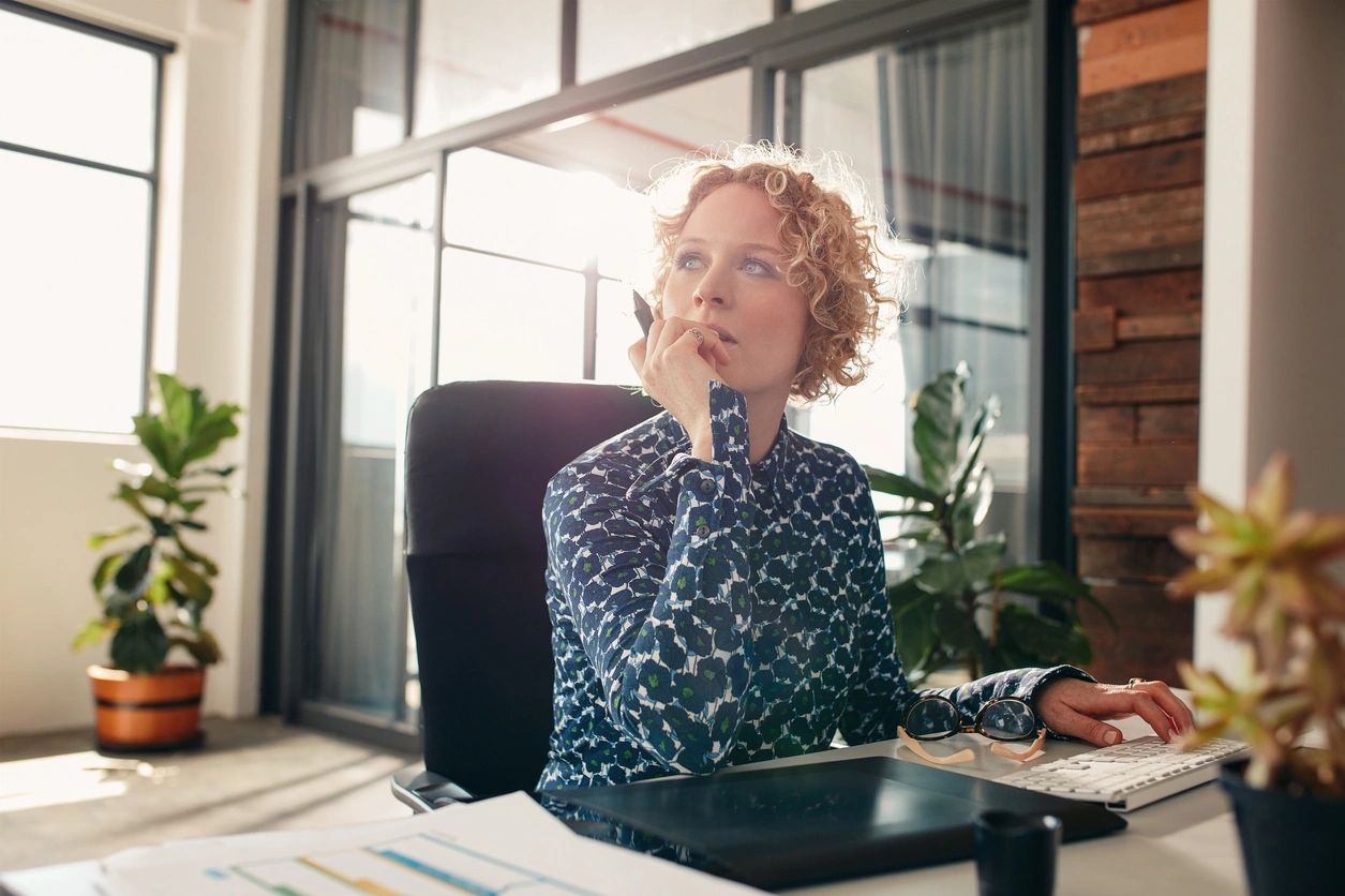 A woman sitting at her desk looking up.